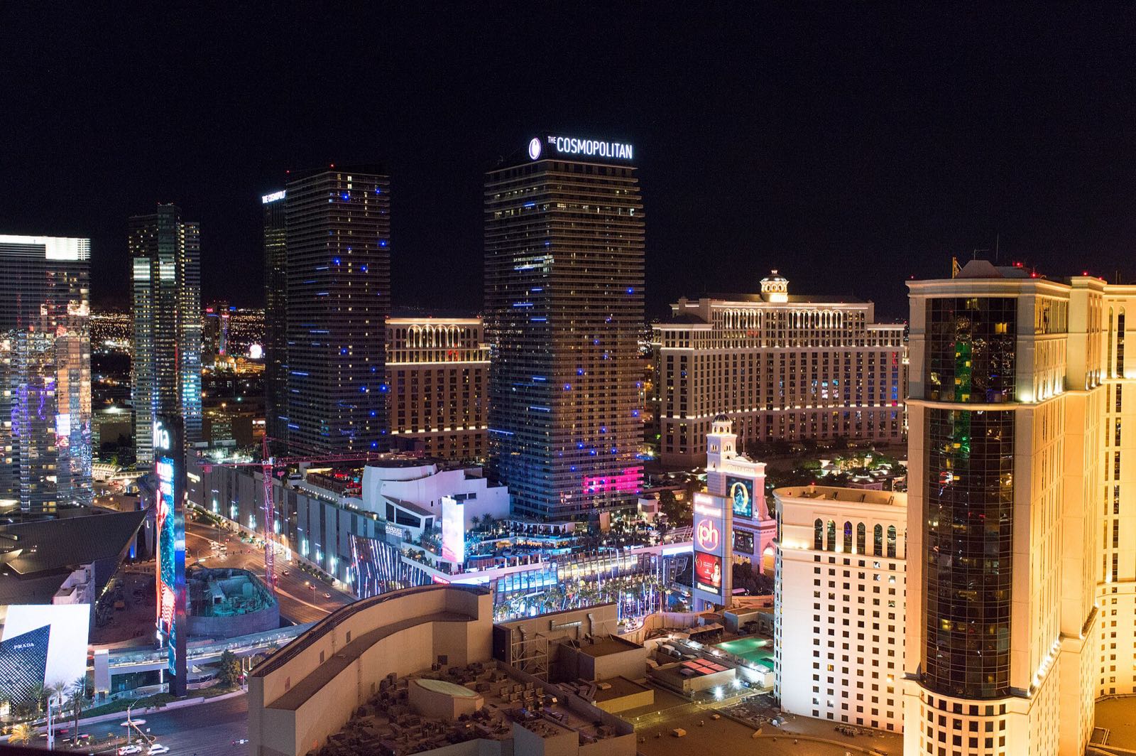 The Las Vegas Strip at night: the glass towers of Aria and Vdara at left, the two Cosmopolitan towers at center, Bellagio behind them and the Planet Hollywood tower at right.